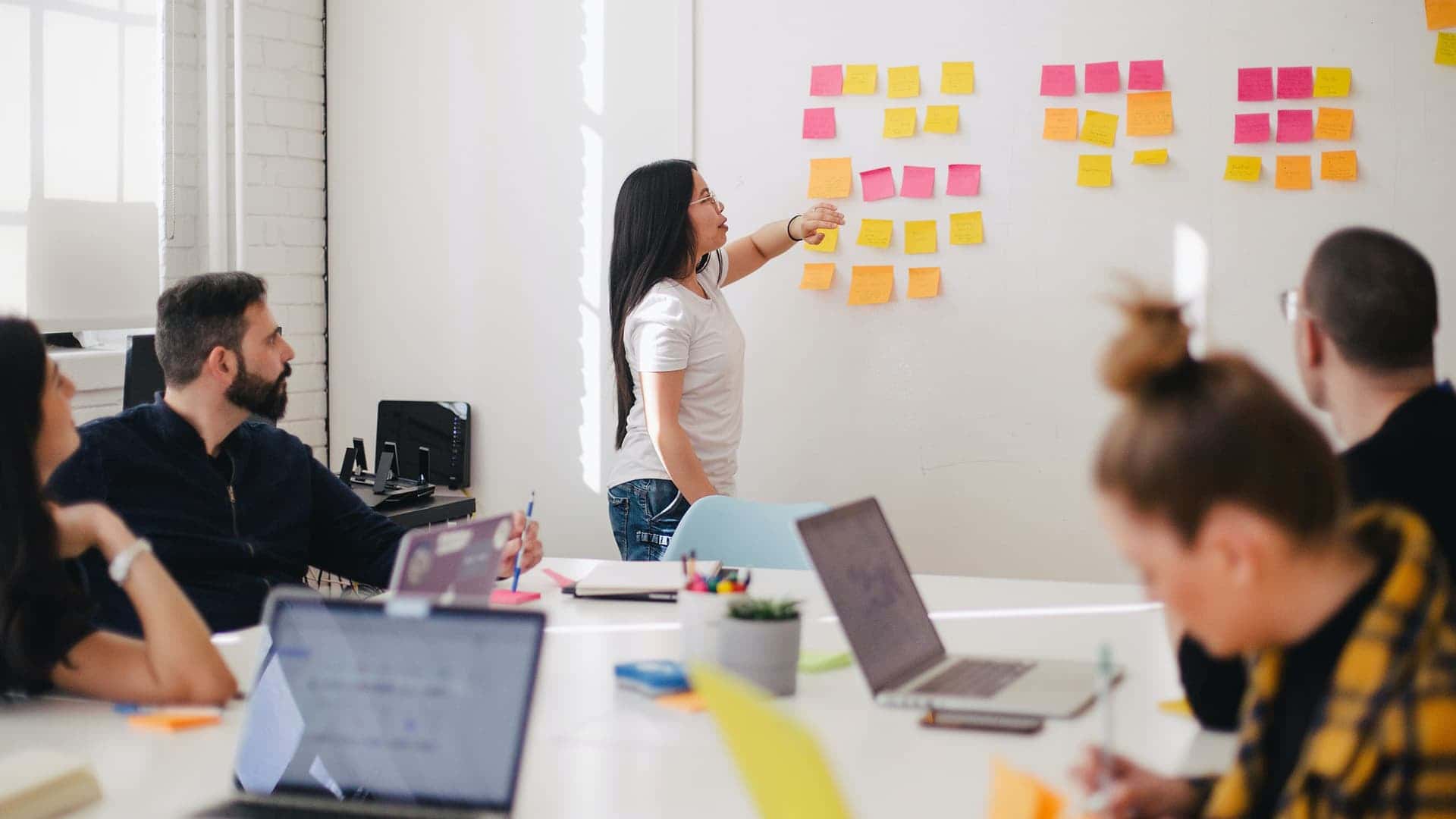 Persona che indica postit colorati sulla lavagna