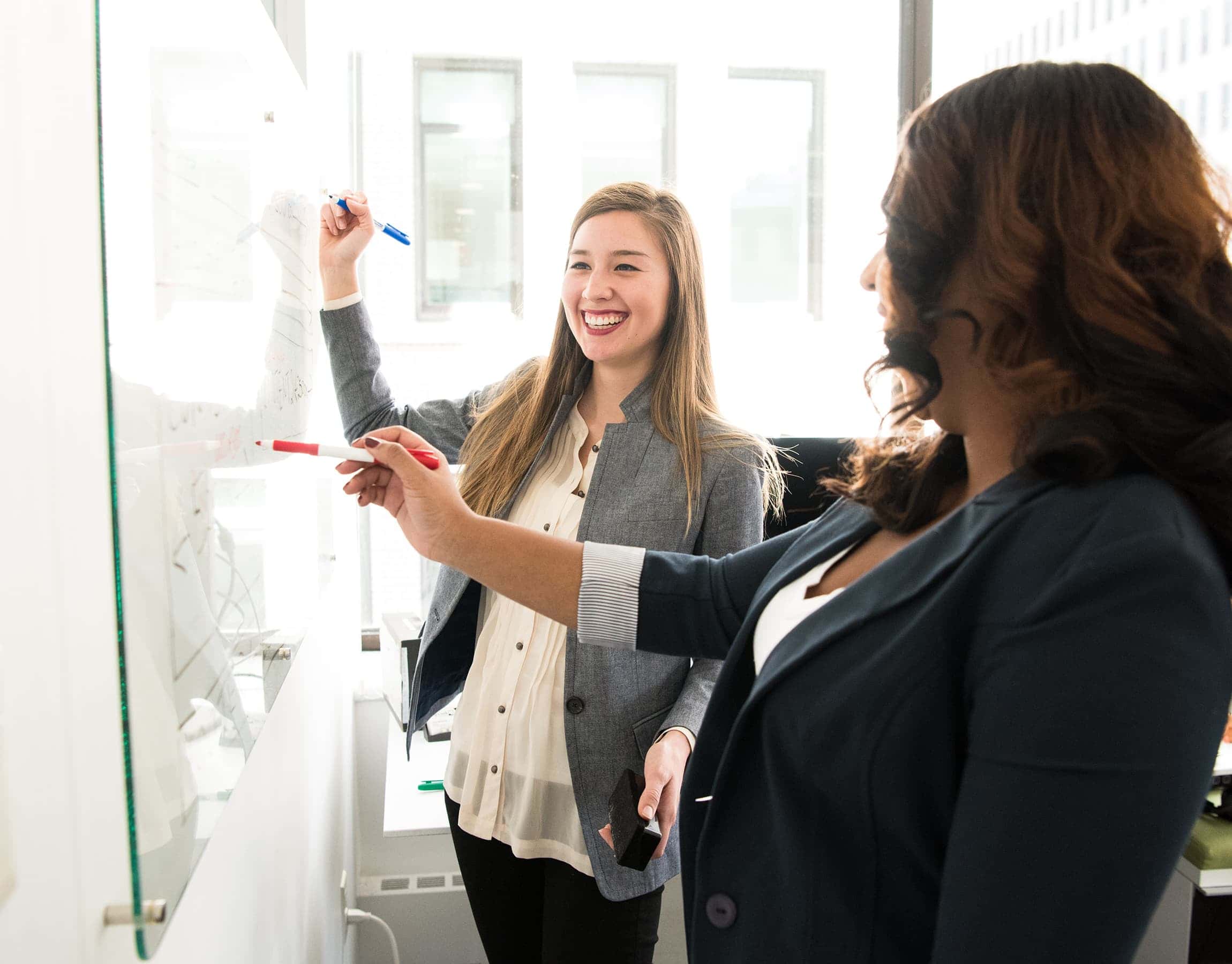 Due donne scrivono appunti alla lavagna dell'ufficio